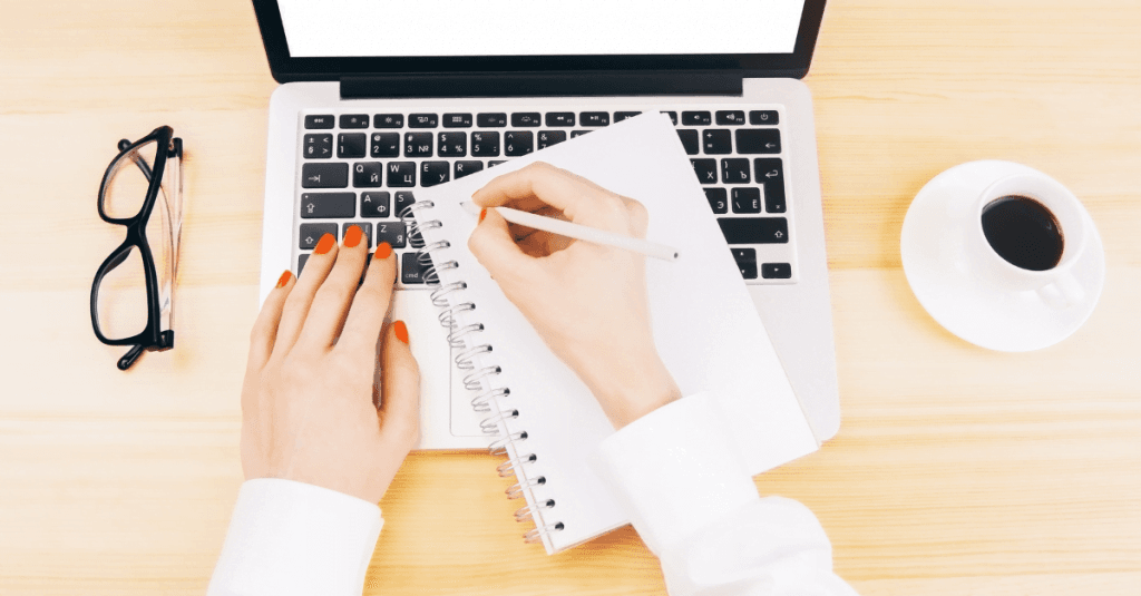 personne qui écrit sur cahier et ordinateur