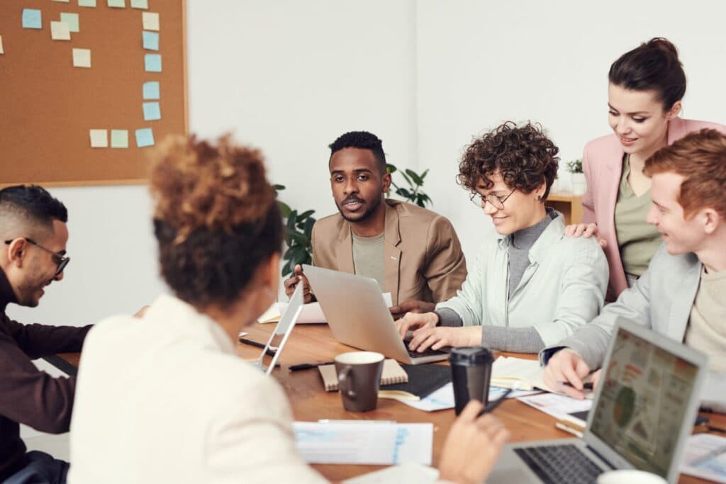 Un groupe de personnes assises autour d’une table avec des ordinateurs portables.